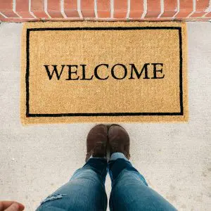 Inclusive Event Planning Makes People Feel Welcome Person standing in front of a welcome mat at the entrance.